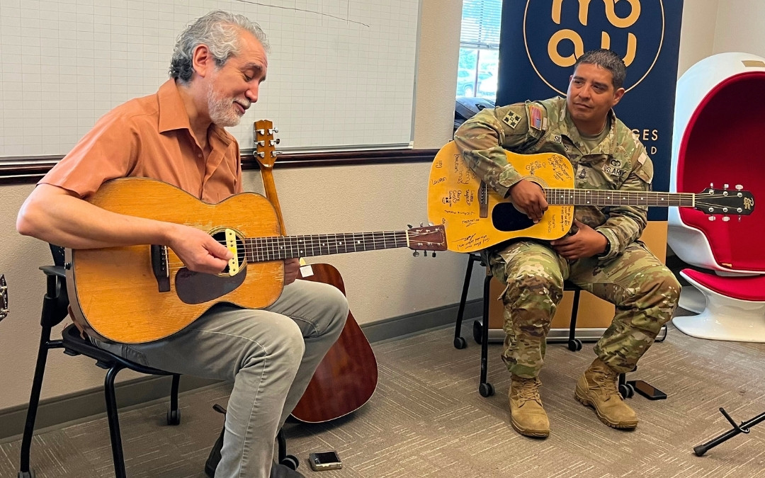 Guitar teacher showing soldier student.